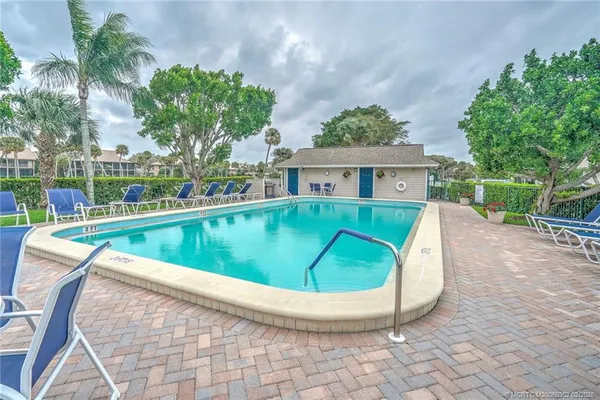 a swimming pool with lawn chairs and plants