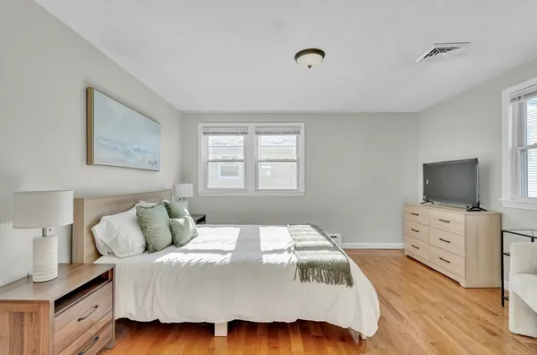 a bedroom with a bed and flat tv screen on the dresser