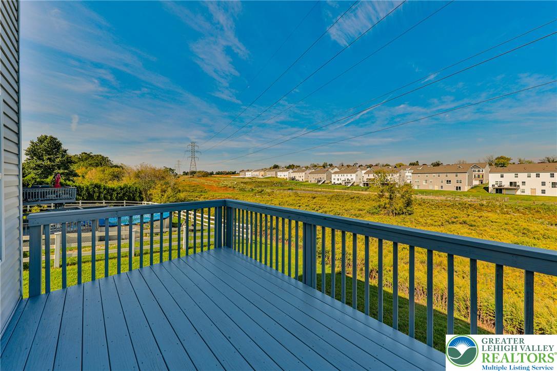 1105 Meco Road Easton, PA 18040 - Photo 85 of 100 An elevated wood deck overlooks a broad grassy field under a bright open sky.