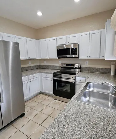 a kitchen with granite countertop a refrigerator stove and microwave