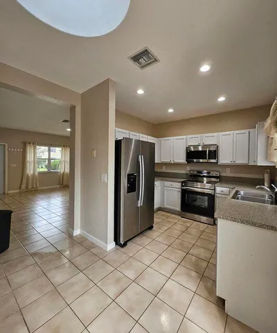 a kitchen with stainless steel appliances granite countertop a refrigerator a stove and a sink