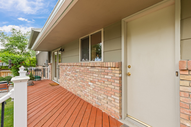 3320 Cherokee Lane Provo, UT 84604 - Photo 41 of 52 Exterior entry featuring a painted door with brass hardware, a brick facade, and a covered wood-finish deck