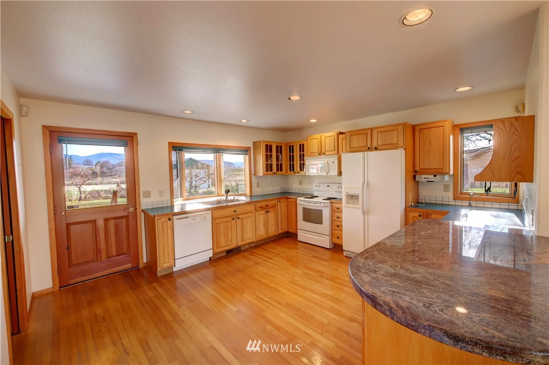 78 Woods Road Omak, WA 98841 - Photo 11 of 40 a kitchen with stainless steel appliances granite countertop a refrigerator a oven a sink with island and chairs