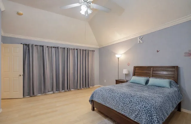 a bedroom with a large bed and a chandelier fan