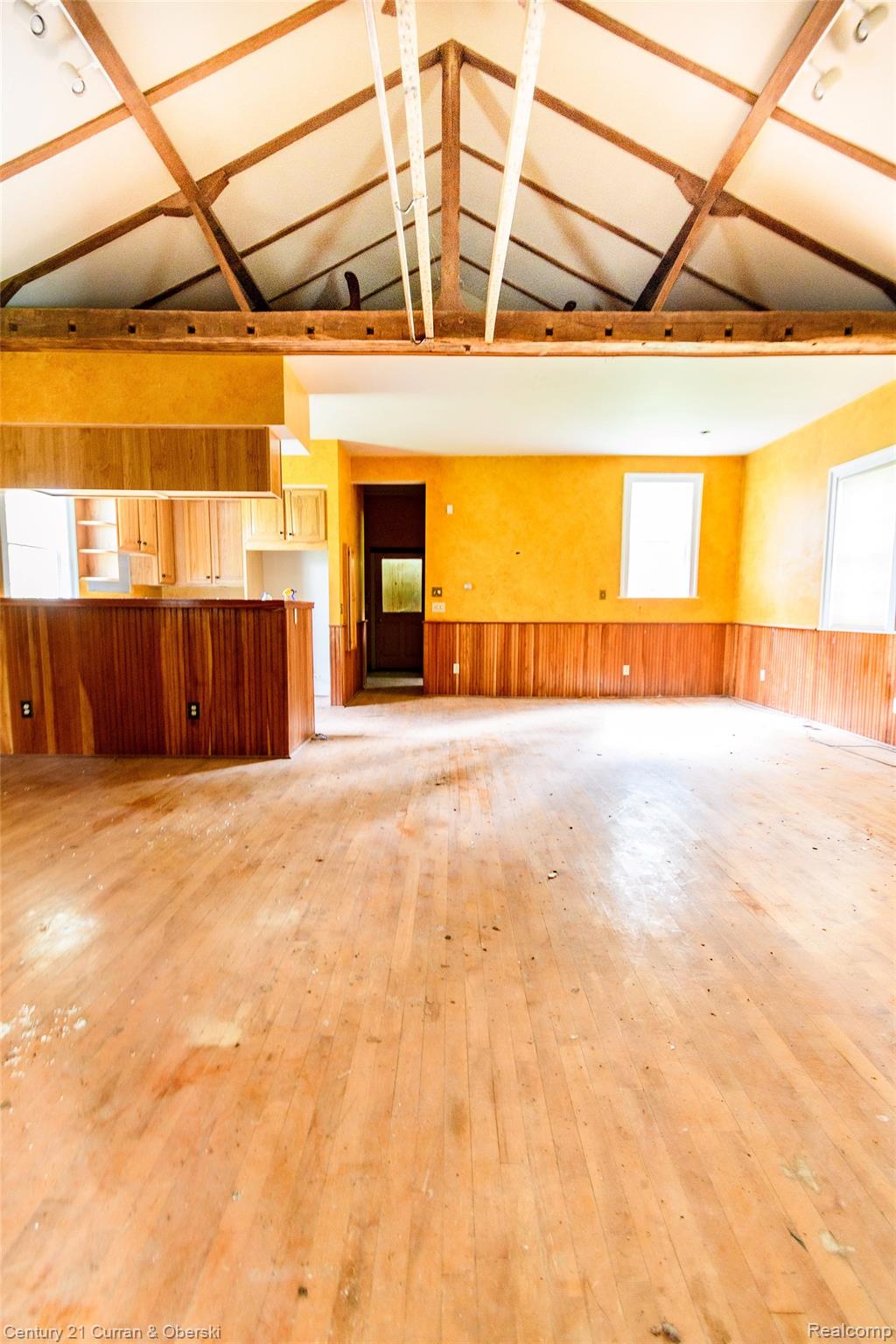 3091 Blackman Road Jackson, MI 49201 - Photo 7 of 17 Exposed beam vaulted ceiling, hardwood flooring, wood paneling, wood kitchen cabinetry, and built-in wood bar with countertop