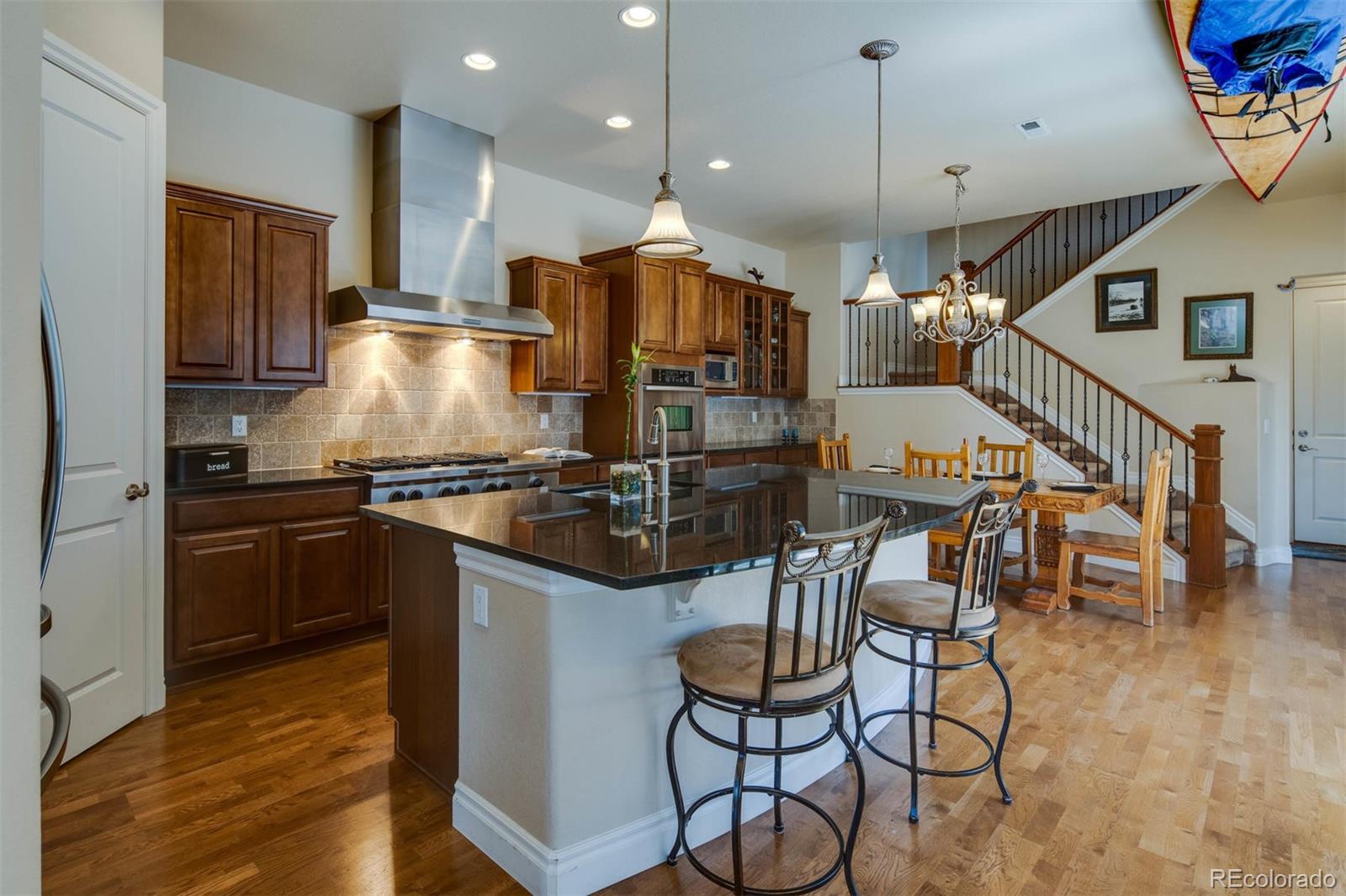 10122 RidgeGate Circle Lone Tree, CO 80124 - Photo 5 of 31 a kitchen with stainless steel appliances kitchen island granite countertop a table chairs and a refrigerator