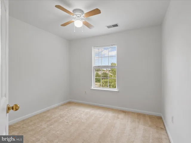 an empty room with a window and a fan