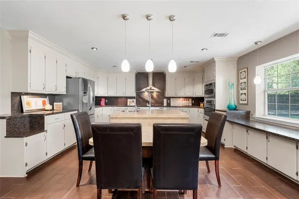 a kitchen with a dining table chairs and white cabinets