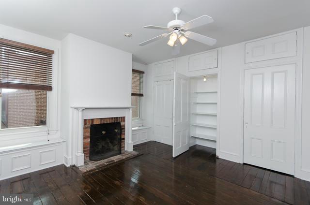 706 E Street Southeast Washington, DC 20003 - Photo 15 of 19 an empty room with a fireplace a ceiling fan and wooden floor