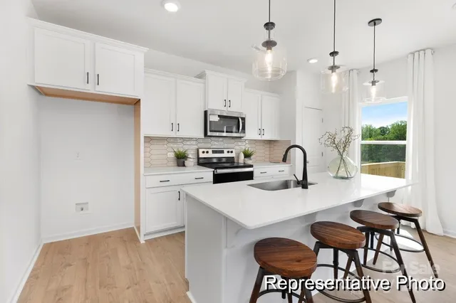 a kitchen with stainless steel appliances granite countertop a stove a sink a microwave a dining table and chairs with wooden floor