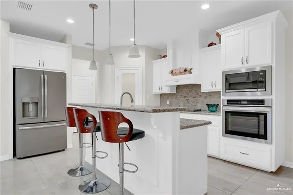 a kitchen with stainless steel appliances kitchen island granite countertop a stove a sink and a refrigerator