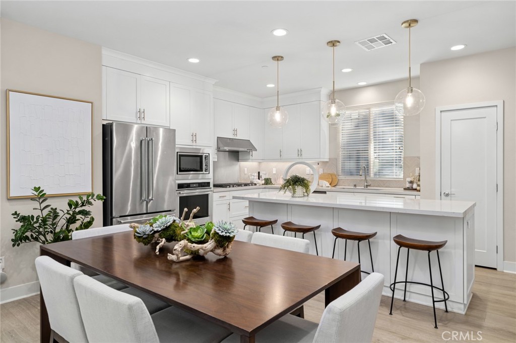 163 Tenor Irvine, CA 92618 - Photo 20 of 40 a kitchen with stainless steel appliances granite countertop a dining table chairs and white cabinets