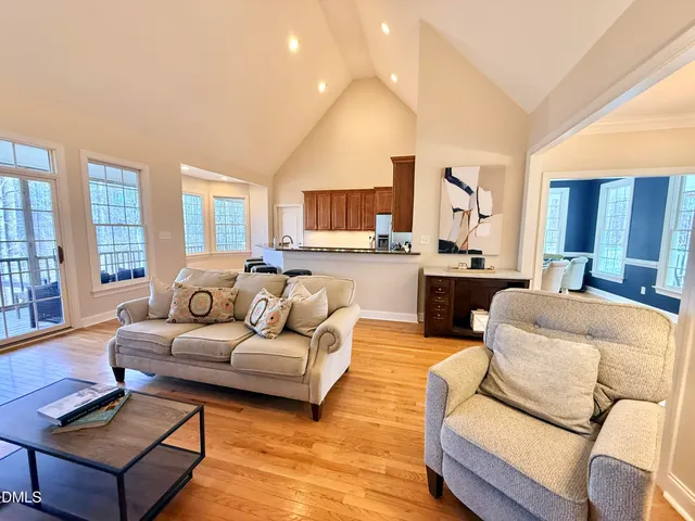 a kitchen with stainless steel appliances granite countertop a stove top oven a sink a dining table and chairs with wooden floor