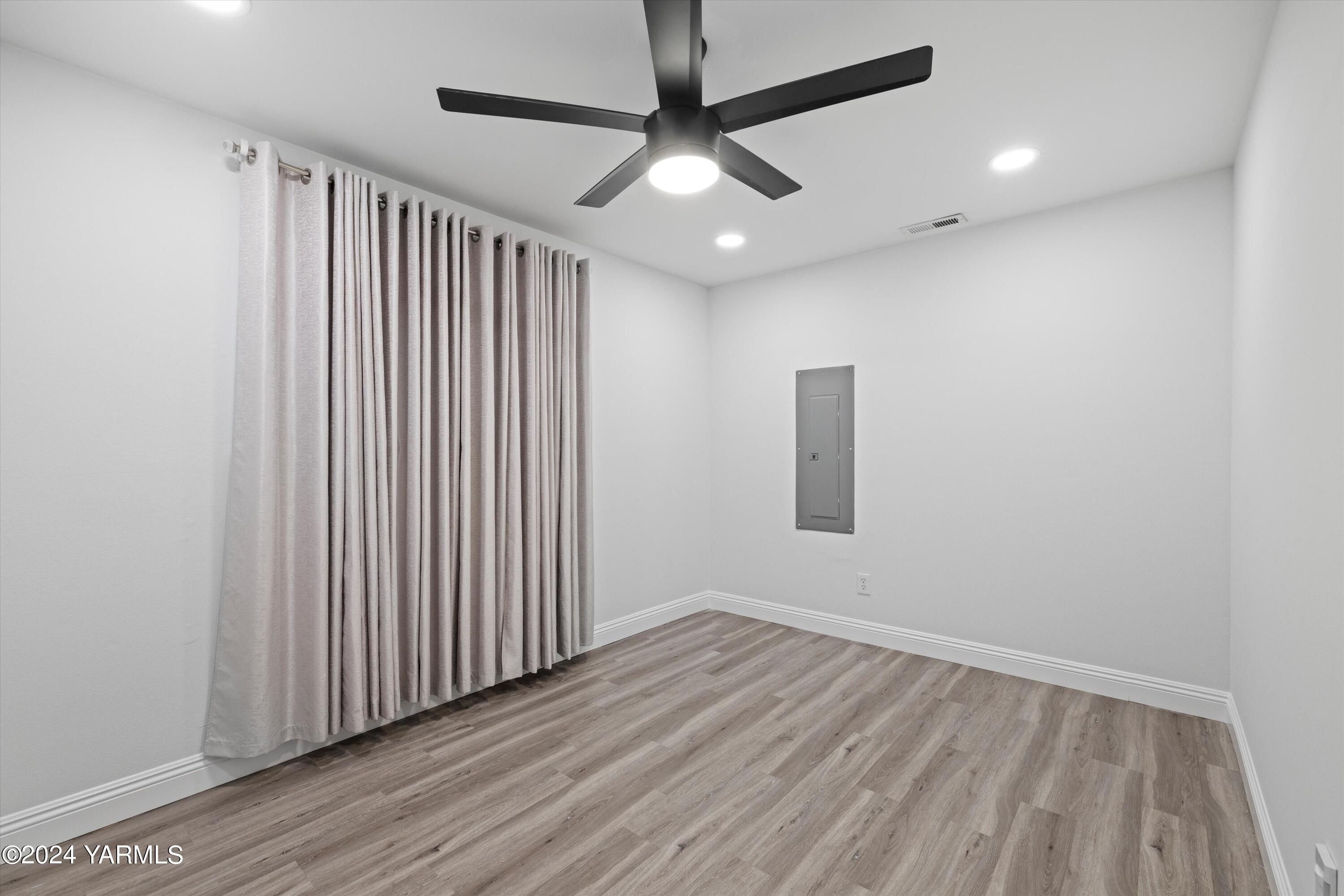 1511 Progressive Road Wapato, WA 98951 - Photo 14 of 36 an empty room with wooden floor chandelier fan and windows