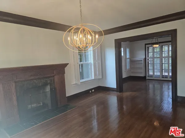 a view of an empty room with wooden floor fireplace and a window