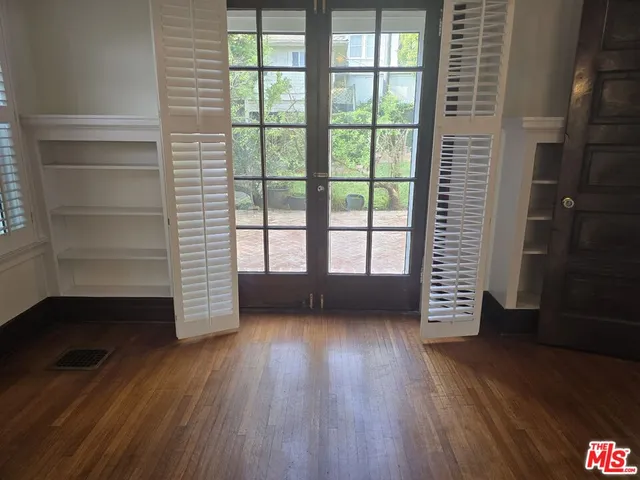 a view of an empty room with a window and wooden floor