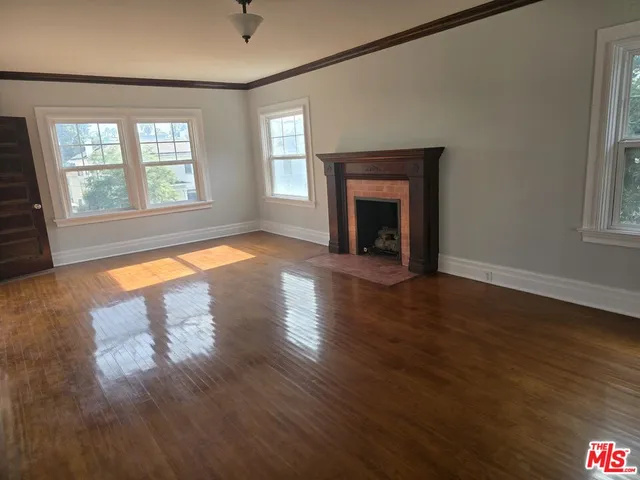 an empty room with wooden floor fireplace and windows