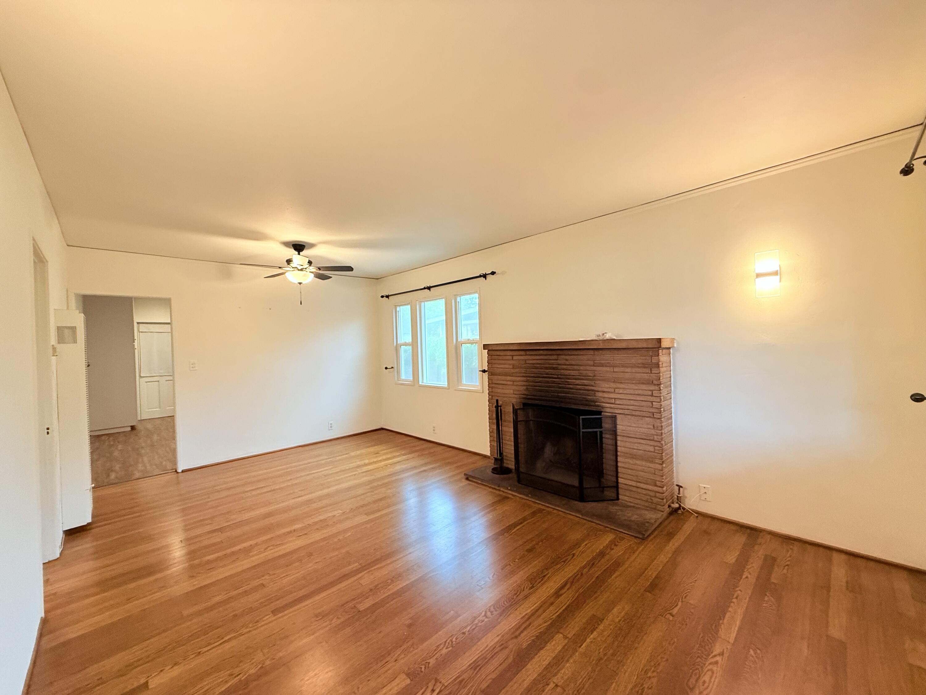 1411 Gillespie Street Santa Barbara, CA 93101 - Photo 5 of 26 an empty room with wooden floor fireplace and windows