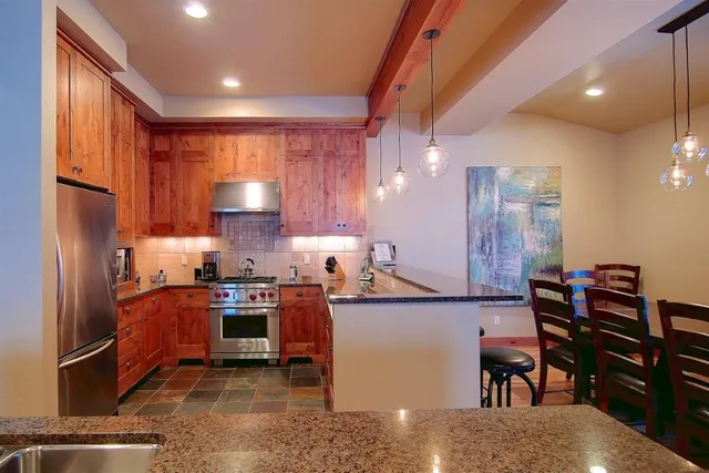 a kitchen with stainless steel appliances granite countertop a refrigerator stove and sink