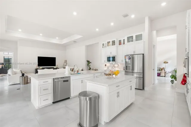 a kitchen with stainless steel appliances kitchen island granite countertop a dining table chairs refrigerator and sink