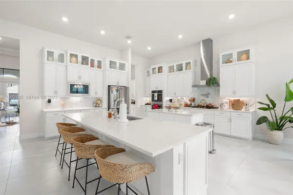 a kitchen with stainless steel appliances kitchen island granite countertop a dining table chairs refrigerator and sink