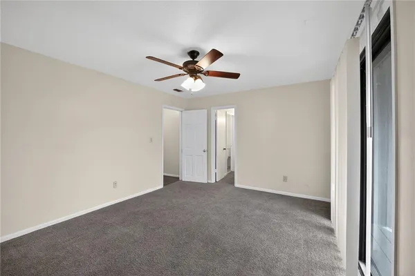 an empty room with a ceiling fan and a window