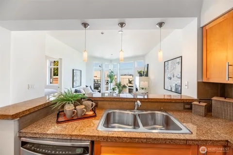 a kitchen with kitchen island granite countertop a sink a counter top space and living room view