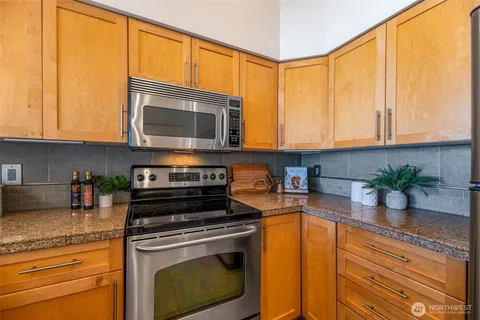 a kitchen with granite countertop a stove a sink and a microwave