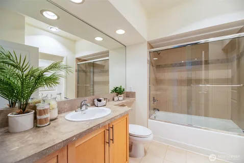 a bathroom with a granite countertop sink a toilet a mirror a vanity and shower