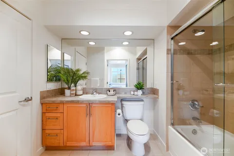 a bathroom with a granite countertop sink toilet a large mirror a shower and a bathtub