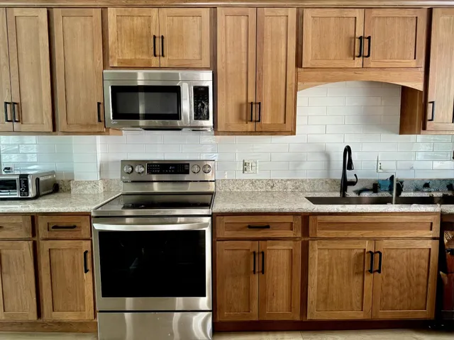a kitchen with stainless steel appliances granite countertop a stove a microwave and wooden cabinets