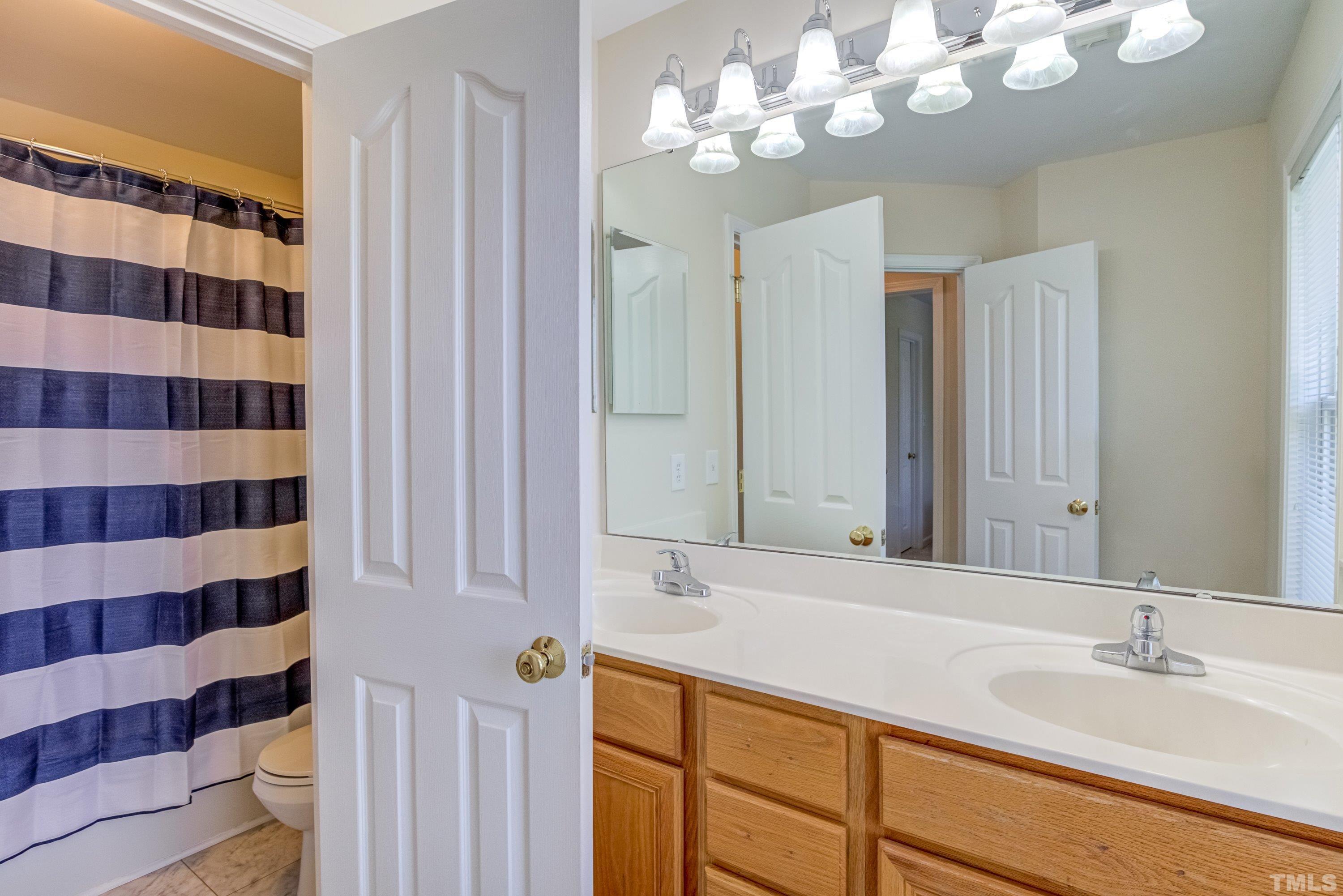 8613 Benzinger Drive Raleigh, NC 27613 - Photo 34 of 48 a bathroom with a sink a mirror and a shower