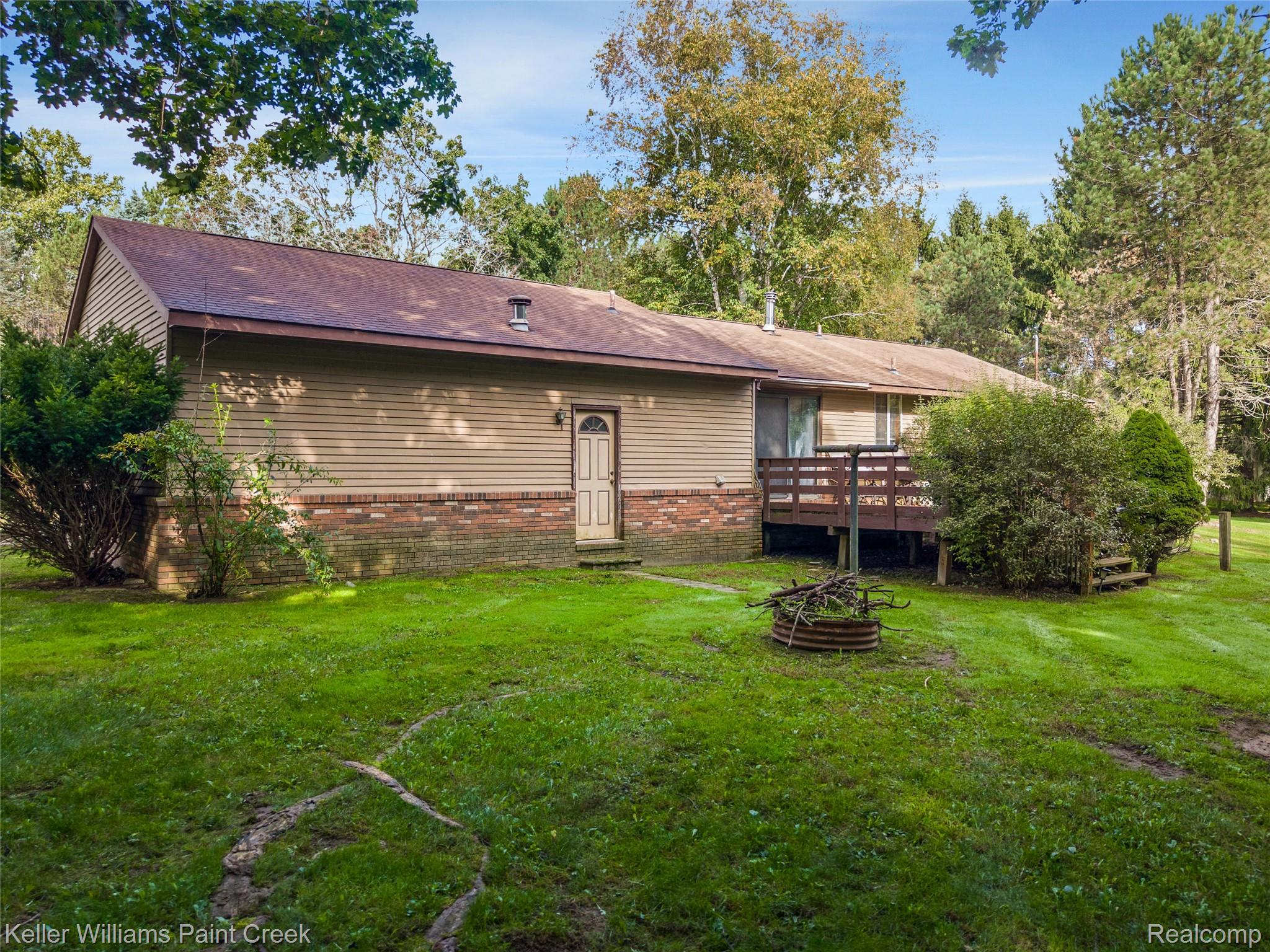 5077 Pinckney Road Howell, MI 48843 - Photo 33 of 39 Expansive backyard featuring a wood deck, mature trees, and a fire pit
