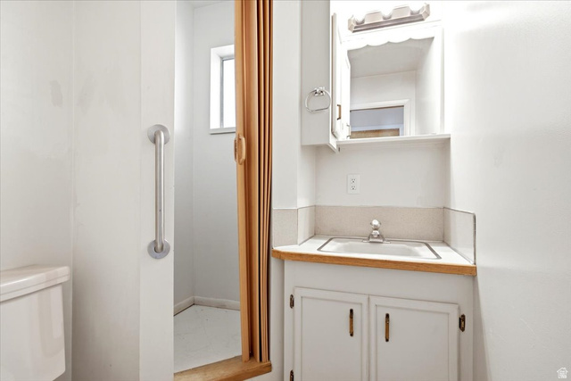 2252 West 800 North Clinton, UT 84015 - Photo 16 of 38 Bathroom vanity featuring a built-in sink, light wood-finish countertop, white cabinetry with brass hardware, and a medicine cabinet with integrated lighting