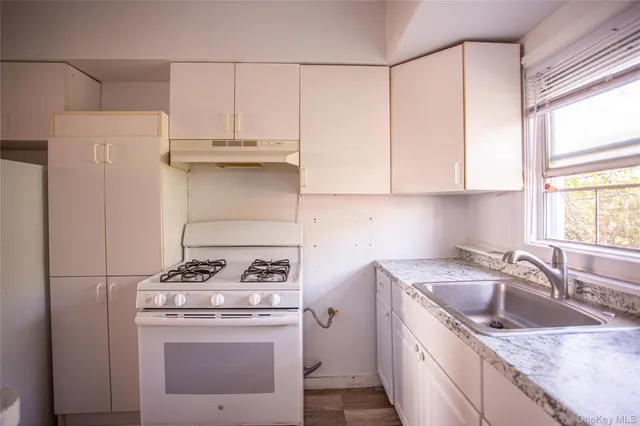 a kitchen with granite countertop a sink stove and refrigerator