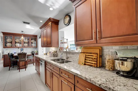 a kitchen with granite countertop a sink a stove and a wooden cabinets