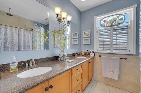 a bathroom with double vanity sinks a vanity a lamp and a window