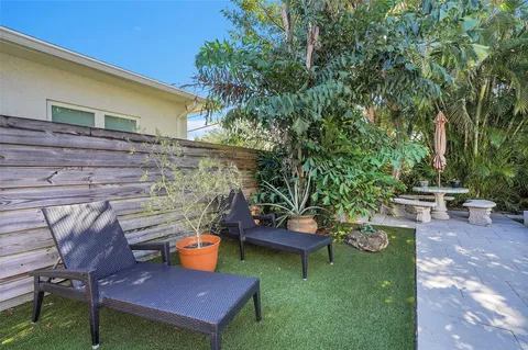 a view of a backyard with chairs potted plants and a patio