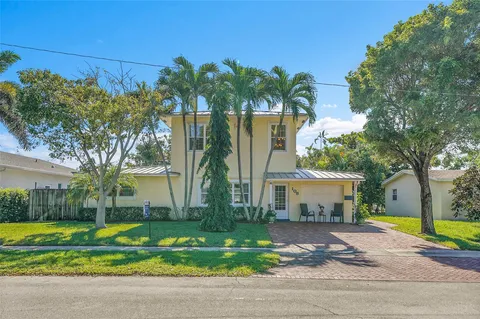 a front view of a house with garden and trees