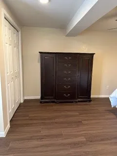 a bedroom with a bed a mirror on the dresser and a table