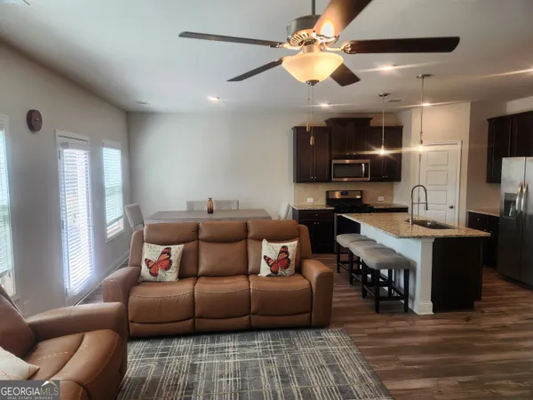 a living room with furniture kitchen view and a chandelier