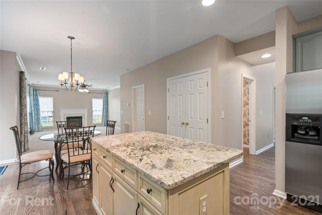 3028 Strawberry Road Matthews, NC 28104 - Photo 8 of 40 a open kitchen with a stove a dining table and chairs with wooden floor