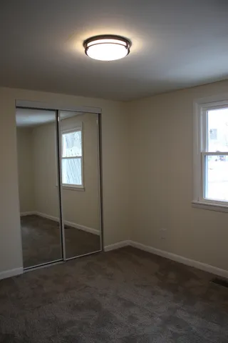 an empty room with closet and windows
