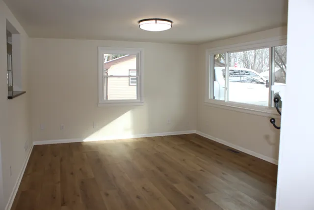 an empty room with wooden floor and windows