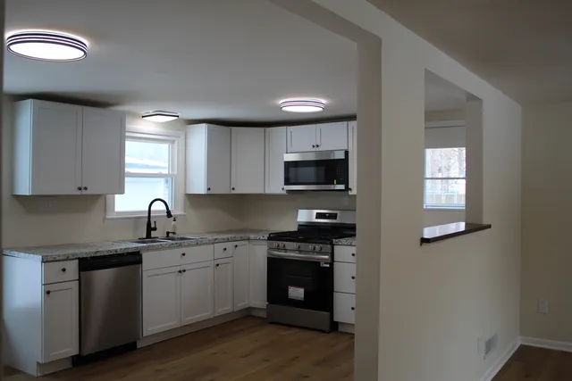 a kitchen with granite countertop a sink cabinets and stainless steel appliances