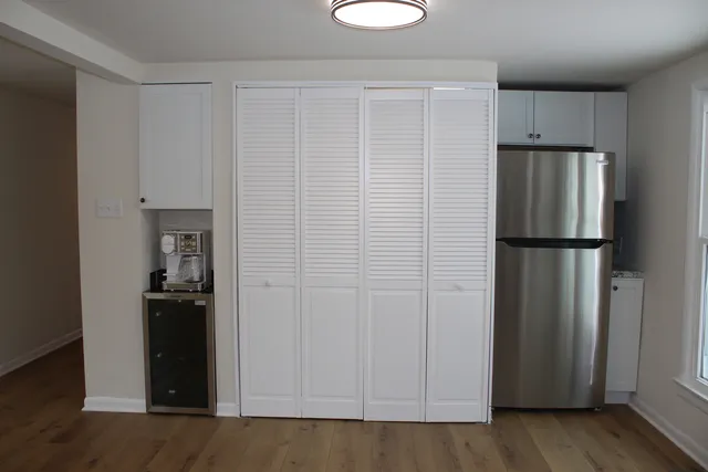a view of a kitchen with refrigerator and wooden floor