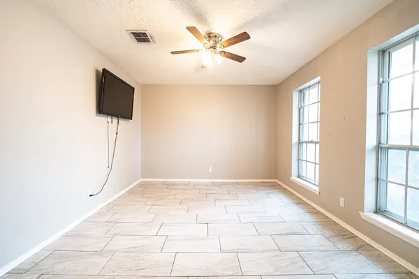 an empty room with windows and ceiling fan