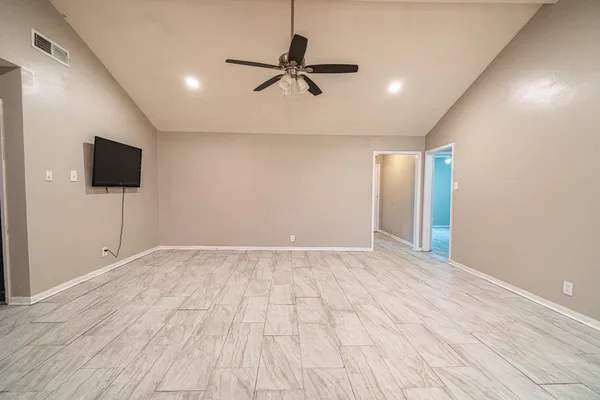 a view of an empty room and a room with a ceiling fan wooden floor and a window