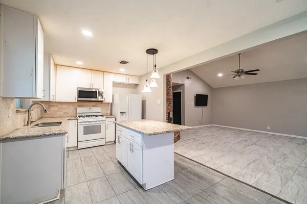 a large white kitchen with cabinets stove top oven and stainless steel appliances