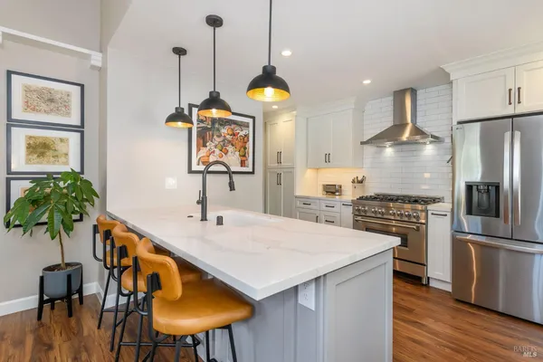 a kitchen with stainless steel appliances kitchen island a table chairs in it and wooden floors